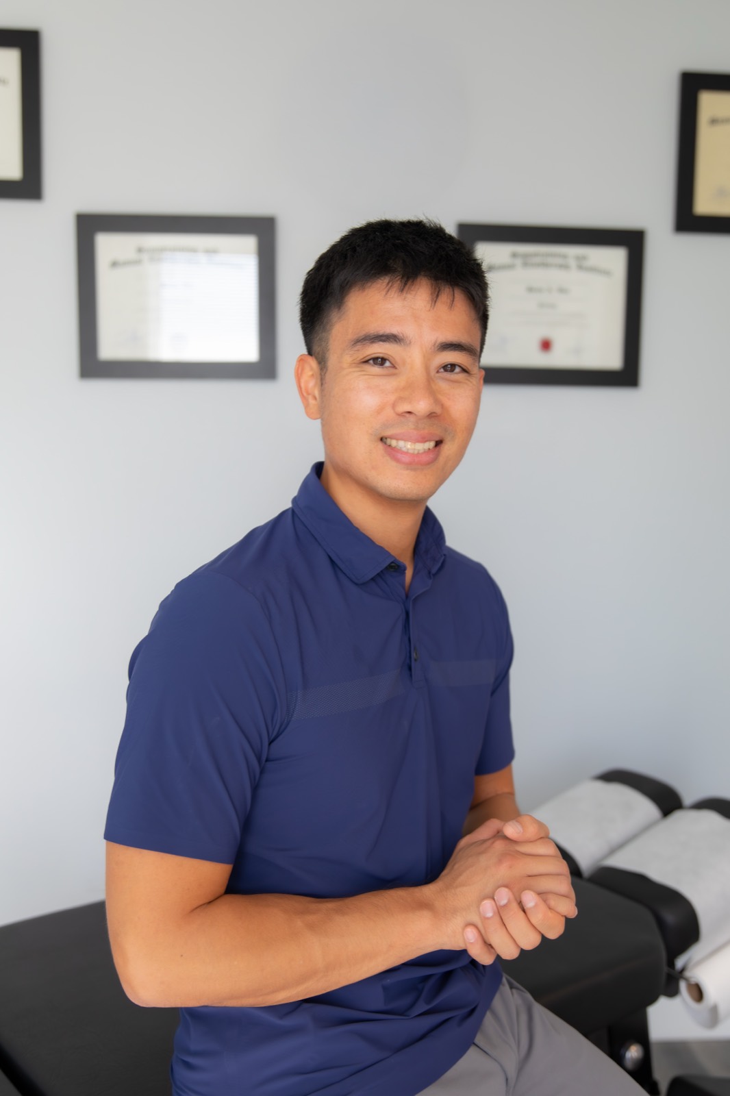 Dr. Jaron Hua, D.C., at G3 Chiro in Newport Beach, with his certifications on the wall behind him