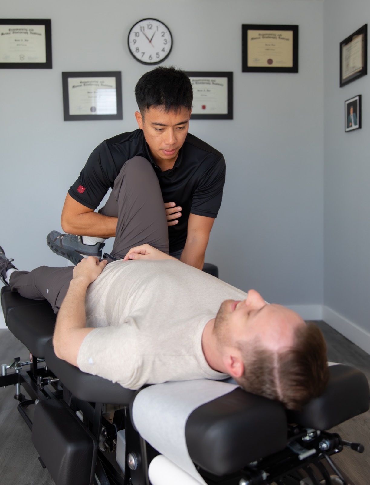 Dr. Jaron Hua mobilizing a patient's hip and leg at G3 Chiro in Newport Beach
