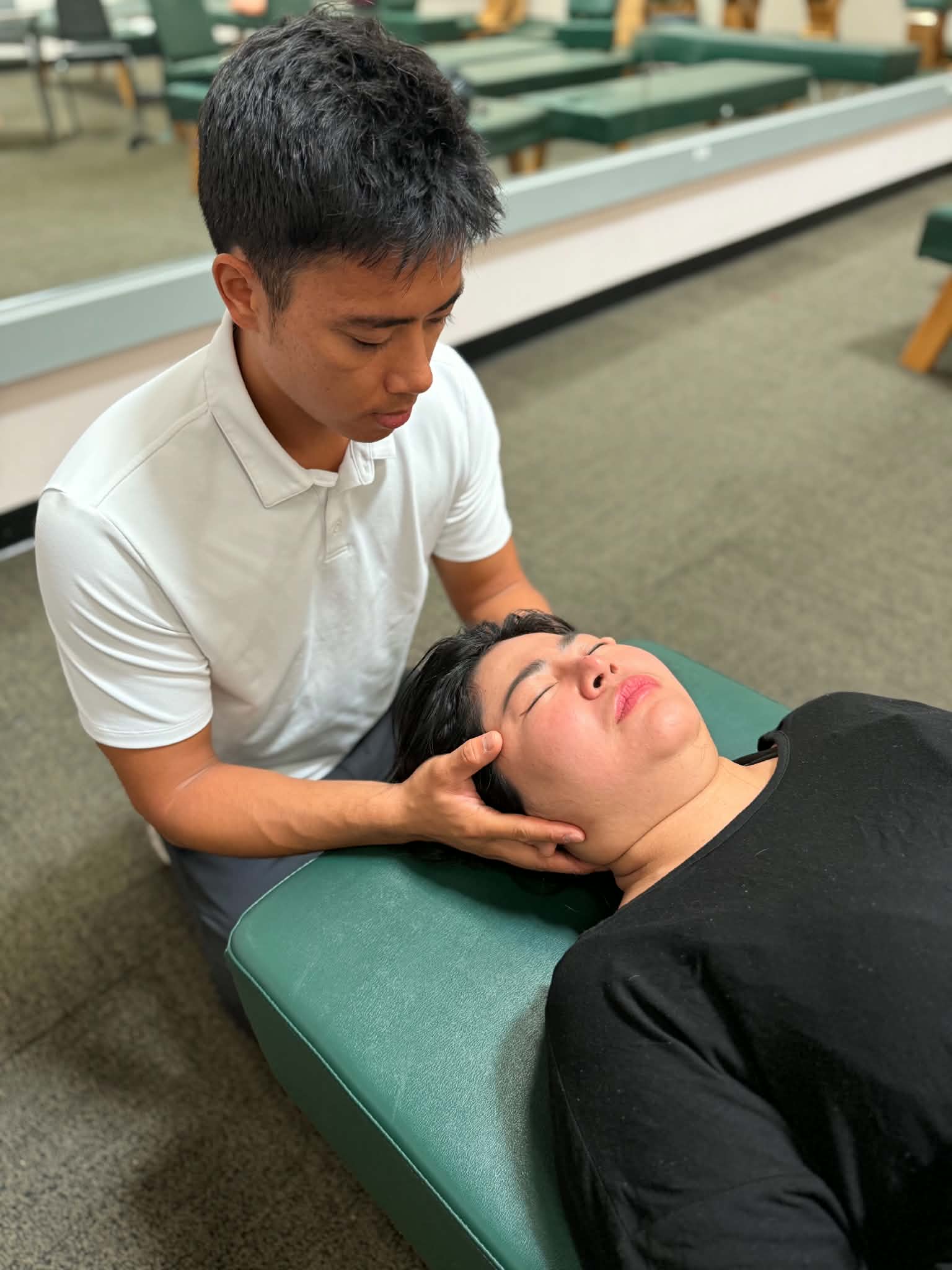 Dr. Jaron Hua treating a patient's jaw while they lie face up at G3 Chiro in Newport Beach