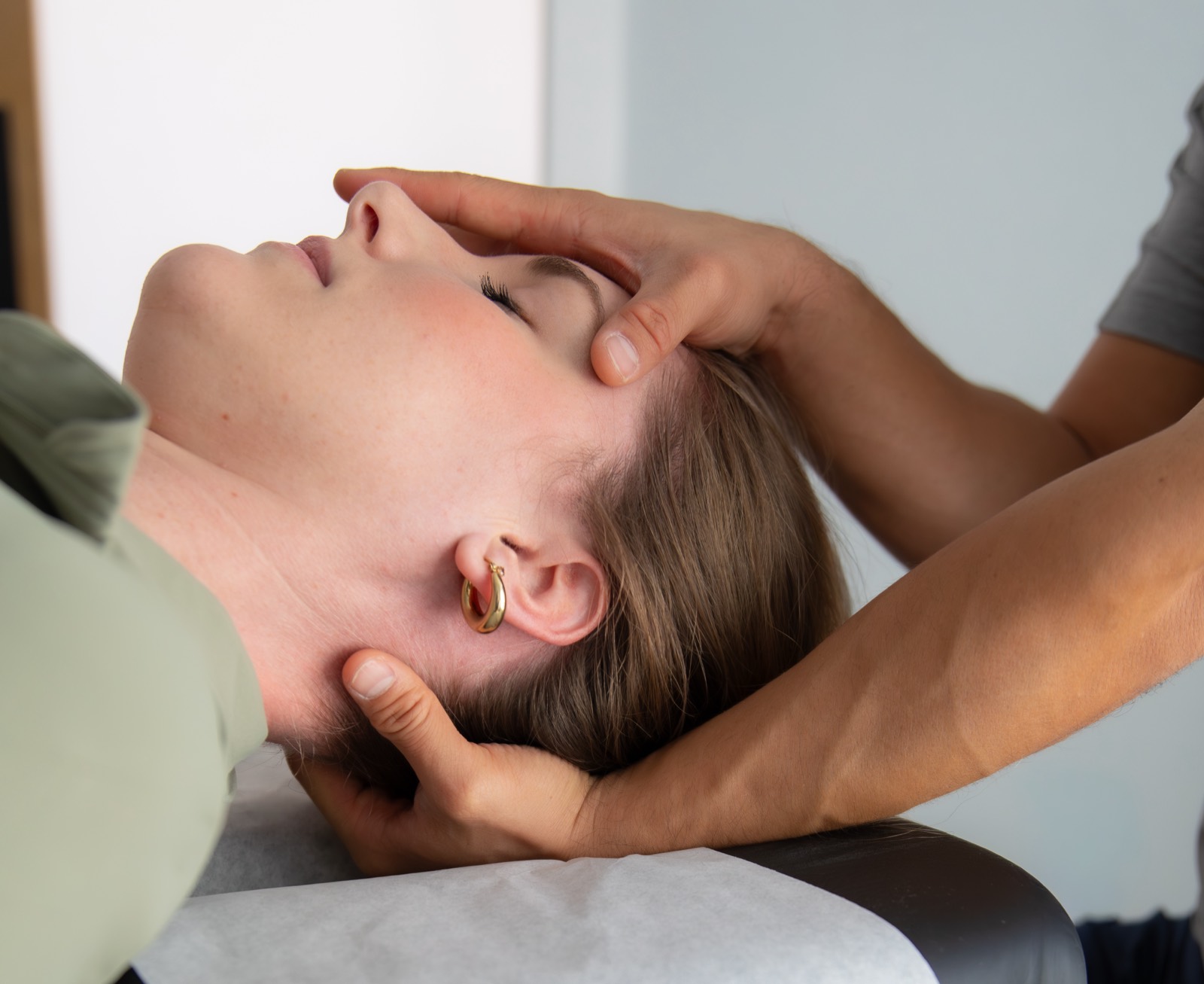 Dr. Jaron Hua supporting a patient's head and neck with both hands during treatment at G3 Chiro in Newport Beach
