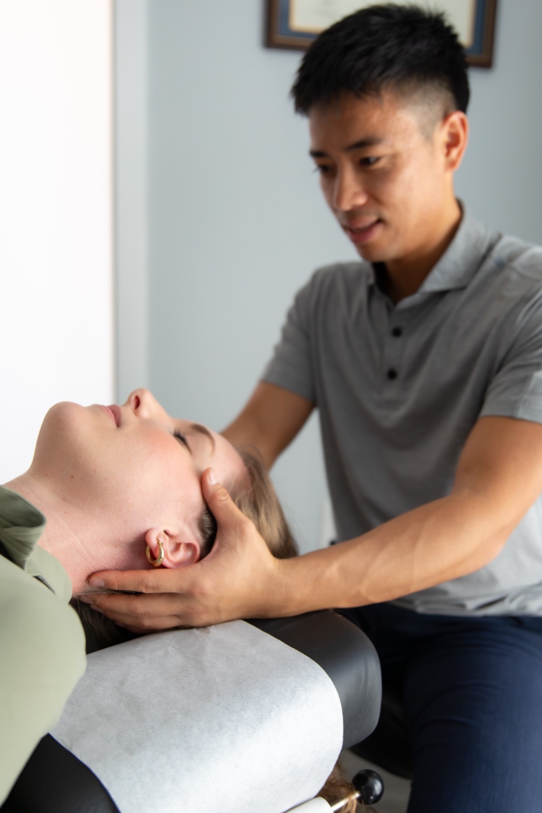 Dr. Jaron Hua supporting a patient's head and neck during treatment at G3 Chiro in Newport Beach