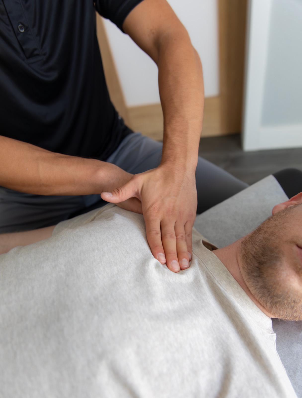 Close-up of Dr. Jaron Hua's hands-on treatment of a patient's upper chest and shoulder at G3 Chiro in Newport Beach