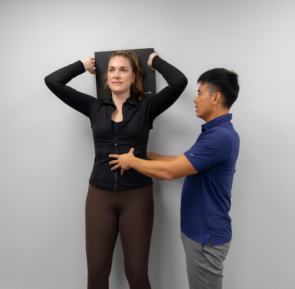 Dr. Jaron Hua coaching a patient’s postural exercise against a wall
